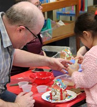 people decorating gingerbread house