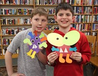 two children holding monster crafts they created