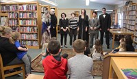 wide shot of theatre guild members speaking in front of library guests