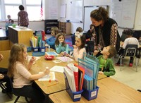 students and teacher working on 100 days of school activity in classroom