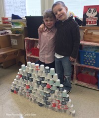 students standing next to tower made from 100 cups