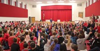 wide shot of auditorium with students raising their hands