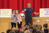 students singing into microphone at assembly