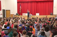 wide shot of student singing in front of assembly