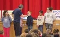 student speaking into microphone in front of assembly