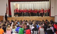 medium shot of high school students performing in front of chenango bridge elementary students