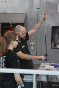 student watching glass be blown