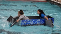 two students competing in cardboard boat races