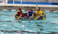 three students competing in cardboard boat races