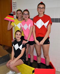 four students standing with their cardboard boat