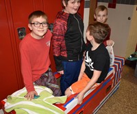 four students sitting in their cardboard boat