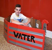 student sitting in cardboard boat