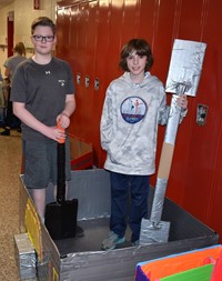 two students standing with their cardboard boat