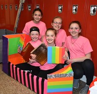 five students sitting with their cardboard boat