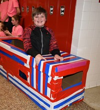 student sitting in cardboard boat