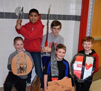 five students standing with their cardboard boat