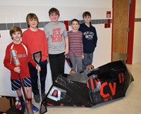 five students standing with their cardboard boat