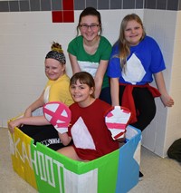 four students with their cardboard boat