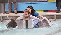 two students competing in cardboard boat race