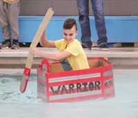 student competing in cardboard boat race