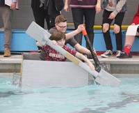 two students competing in cardboard boat race