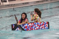 two students competing in cardboard boat race