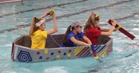 three students competing in cardboard boat race
