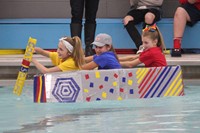 three students competing in cardboard boat race