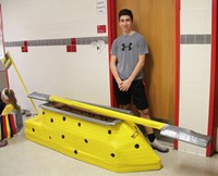 student standing with cardboard boat