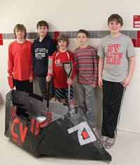 five students standing with cardboard boat