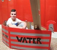student sitting in cardboard boat