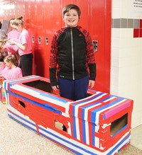 student standing with cardboard boat