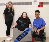 three students with cardboard boat