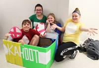 four students with cardboard boat