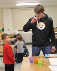 high school student demonstrating activity for younger student