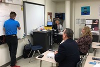 administrators watching steam night demonstration from high school student