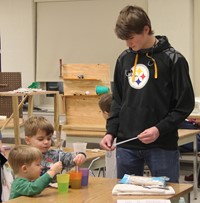 younger students taking part in activity with high school student