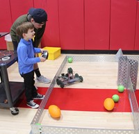 high school student helping younger student with robotics activity