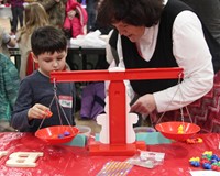 teacher helping student with steam night activity involving weighing plastic bears