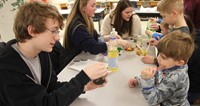 high school student showing younger student magnetic experiment