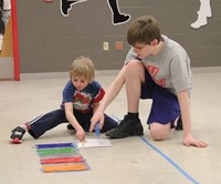 middle school student helping younger student with steam night activity