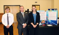 two students next to project with superintendent