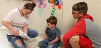 high school and middle school students reading to kindergarten students 5