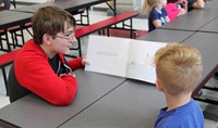 high school student reading to kindergarten student 12