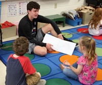 high school student reading to kindergarten students 7