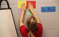 student hanging up kind sign