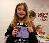 student holding up thank you card