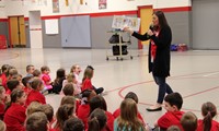 school counselor reading book to students at morning presentation