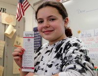 student smiling holding bookmark with random acts of kindness