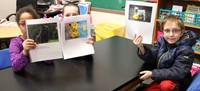 three students holding up stories